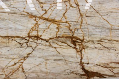 Calacatta Macchia mermerinin dokusu beyaz arka planı ve zarif, kalın kahverengi damarları var.