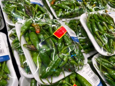 Jakarta, Endonezya - 08 Şubat 2026: GrandLucky sebze rafında plastiğe sarılı taze yeşil kuş gözü kırmızı biber frutesans ayrıntıları.