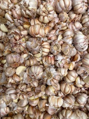 Tam bir sarımsak ya da Allium sativum koleksiyonu ve temel yemek pişirme baharatı olarak satış rafında soyulmuş birkaç karanfil..