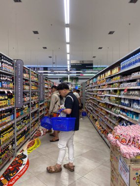 Jakarta, Endonezya - Şubat 08 2026: GrandLucky süpermarketinin C-6 koridorundaki mutfak baharat rafında Endonezya soya sosu ürünlerini seçen erkek müşteri.
