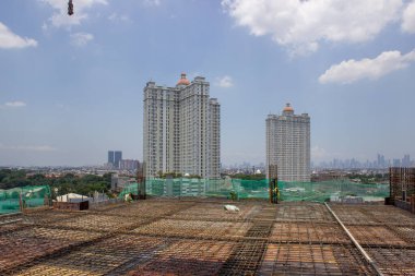 Işıl ışıl mavi gökyüzünün altındaki bir inşaat alanından iki yüksek katlı apartman manzarası