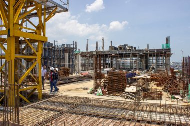 Jakarta, Endonezya - 16 Mart 2026: Mühendislerden oluşan bir ekip, arka planda beton çerçeve ile geliştirme aşamasındaki bir inşaat alanında tartışıyorlar.