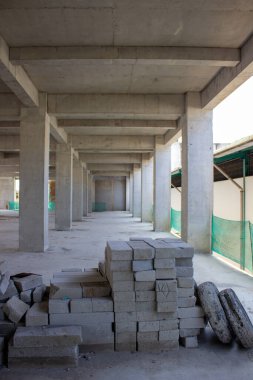 Bitmemiş beton yapısal sütunları olan bir inşaat binasının beton zemininde hafif tuğla yığını ya da hebel