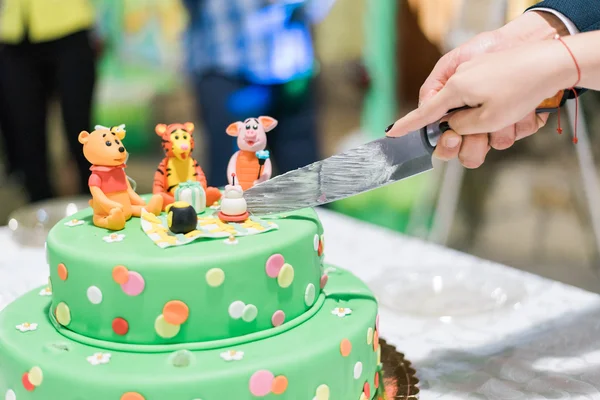 Cortando o bolo de aniversário com velas e Winnie the Pooh pela Disney — Fotografia de Stock