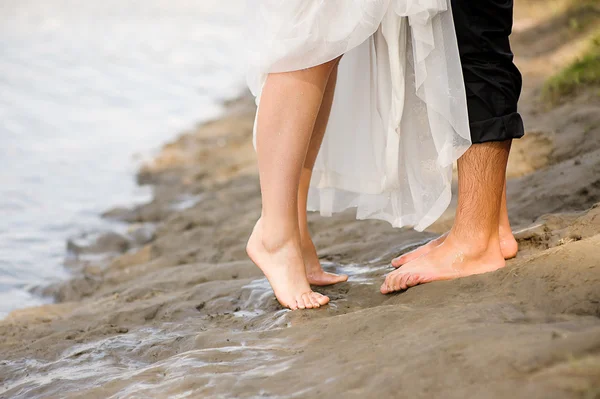 Kärleksfull ungt par kramar, kyssar på stranden i solnedgången — Stockfoto