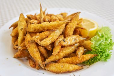 Small fried fish, A small dish of fried whitebait with slices of lemon. This would be served as a starter or tapas in Spain. clipart