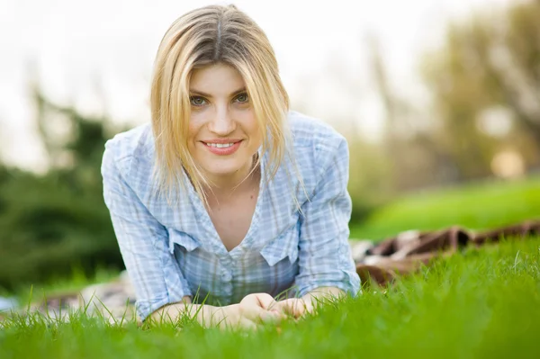 Portrait of a beautiful woman laying in the grass with a smile Stock Photo