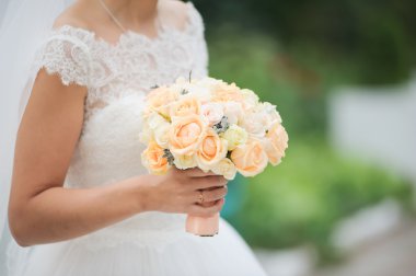 Gelin elinde bir buket çiçek tutuyor.