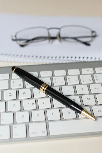 Schwarzer Stift mit Tastatur und Brille mit weißem Block oder Notizblock — Stockfoto