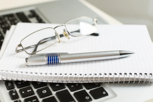 Laptop mit Notizblock, Stift, Brille und Tastatur — Stockfoto
