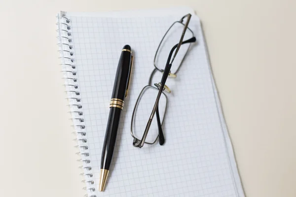 Black pen and glasses with white pad or notepad Stock Image