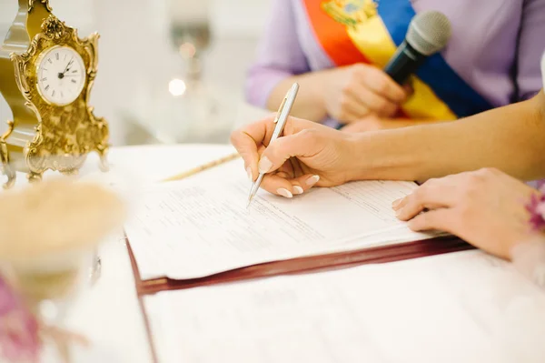 Bride signs marriage certificate with a pen — Stock Photo, Image