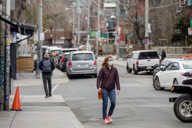 Toronto 'nun Kensington pazarında kadın yüz maskesi takıyor. İnsanlar COVID-19 salgınından dolayı maske ve eldiven takıyor..