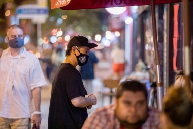 Garson müşterilere servis yaparken yüz maskesi takıyor. Toronto 'daki restoranların COVID-19 salgını sırasında içerideki yemek kısıtlamaları nedeniyle kaldırımlara ve sokaklara veranda kurmalarına izin verildi.. 