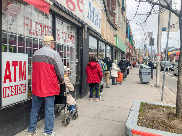 People practice social distancing while waiting in line to enter store during COVID-19 Pandemic.