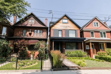 TORONTO, CANADA - AUGUST 21, 2017: BIG HOMES ON RESIDENTIAL STREET IN HIGH PARK/RONCESVALLE NEIGHOURHOOD. clipart