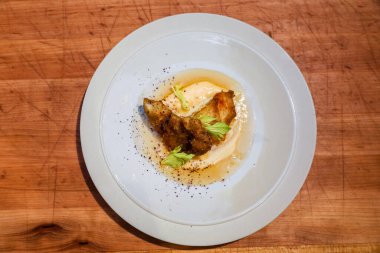 Ahşap masada seramik tabakta servis edilen lezzetli yemekler.