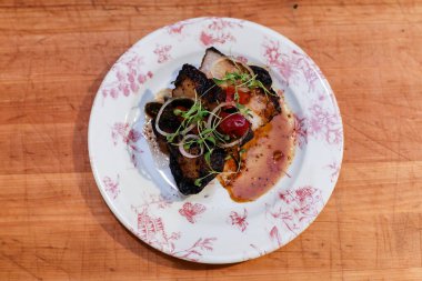 Ahşap masada seramik tabakta servis edilen lezzetli yemekler.