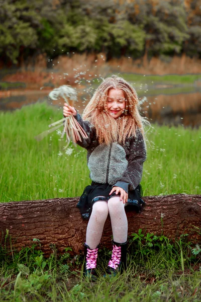 Blondes Mädchen mit Löwenzahn auf einer Lichtung Spaß. — Stockfoto