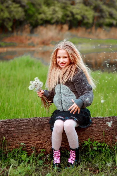 Блондинка с одуванчиками на поляне весело . — стоковое фото