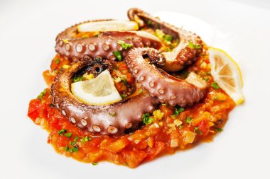 Daha önce zeytinyağı, kekik, tuz ve biber Marine Izgara ahtapot pişmiş. Domates, havuç ve pırasa, tavada bir yatağın üzerinde. Son olarak, maydanoz ve limon sıkmak.