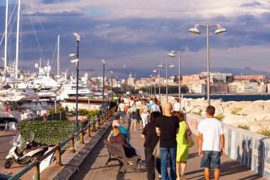 İnsanlar gün batımında tekne yanındaki iskelede yürüyüş yapın.