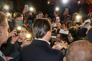 Roma, İtalya - 15 Ocak 2016: Leonardo DiCaprio 'nun sokakta halka imza dağıtması. Aktörün etrafı İtalyan hayranlar ve güvenlik görevlileriyle çevrili. Halka açık bir yerdeyiz, onu alacak olan kırmızı marangoza girmeden önce. 