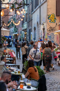 Roma, İtalya - 26 Mayıs 2021: Trastevere, tarihi şehir merkezinin sokakları aperatif veya akşam yemeği için açık masalarda oturan turist ve vatandaşlarla dolu.