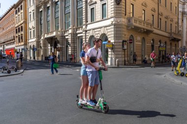 Roma, İtalya - 26 Ağustos 2021: İki erkek çocuğu şehir merkezinin sokaklarında gezmek için elektrikli scooter kullanıyor.