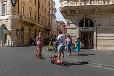 Roma, İtalya - 26 Ağustos 2021: İki erkek çocuğu şehir merkezinin sokaklarında gezmek için elektrikli scooter kullanıyor.