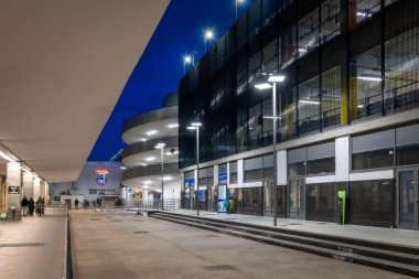 Napoli, İtalya - 26 Aralık 2025: Günbatımında Napoli Merkez İstasyonu ulaşım merkezinin aydınlatılmış dış kısmı, modern park tesislerini ve yaya geçitlerini göstermektedir..