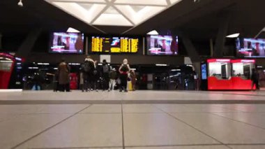 Napoli, İtalya - 19 Şubat 2026: Napoli Centrale 'nin ana koridorunda yürüyen gezginlerin hızlı akışını gösteren geniş bir zaman atlaması. Hareket bulanıklığı, dijital panoların titremesiyle modern tavan altındaki kalabalığın geçişini vurguluyor..