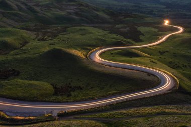 Kıvrımlı kırsal yol, İngiliz kırsalından geçen farlardan gelen ışık izi..