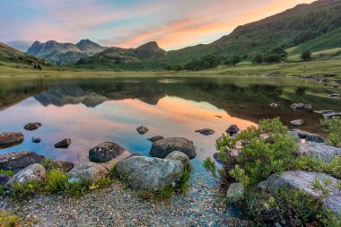 Gün doğumunda dağ yansımaları. Blea Tarn, Lake District, İngiltere.