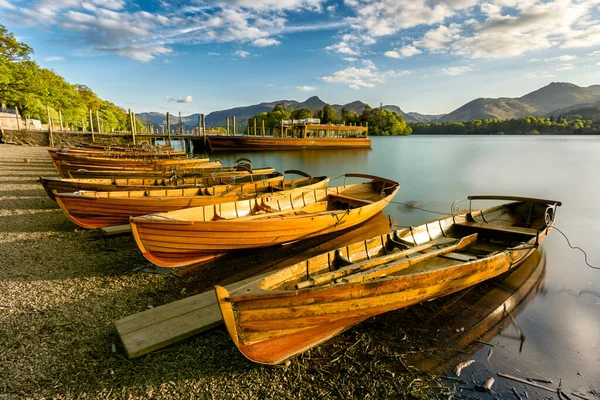 Beautiful evening golden light shining on row of rowing boats at Keswick Boat Launch in the English Lake District.