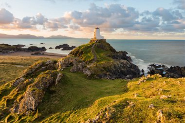 Kuzey Galler 'deki beyaz deniz fenerinde güneşli bir sabah ışığı. Ynys Llanddwyn, Anglesey, İngiltere.