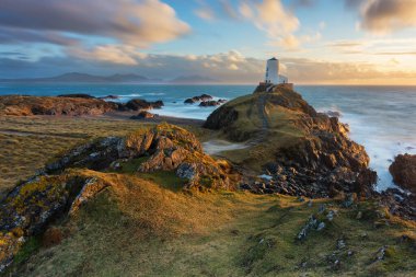 Galler sahilindeki beyaz deniz fenerinin üzerinde dramatik bir gökyüzü. Ynys Llanddwyn.