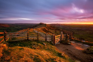 Güneşin doğuşundan parlayan kırmızı ışık, Mam Tor 'un kırsal kapısında karamsar bulutlarla parıldıyor..