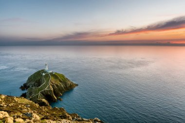 Holyhead, Kuzey Galler 'deki South Stack' te ufuk ve güzel günbatımı olan sahil adasındaki deniz feneri..