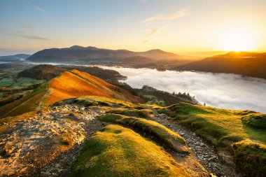Güneşli, sakin bir sabahta gölün üzerinde bulut sisi olan Catbell 'den Derwentwater' a bakan güzel bir gün doğumu. Lake District Ulusal Parkı, İngiltere.