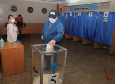 Bir sonraki yerel seçimlerde, Kiev 'deki oy kullanma merkezlerinden birinde, 25 Ekim 2020' de bir seçmen sandığa oy attı..