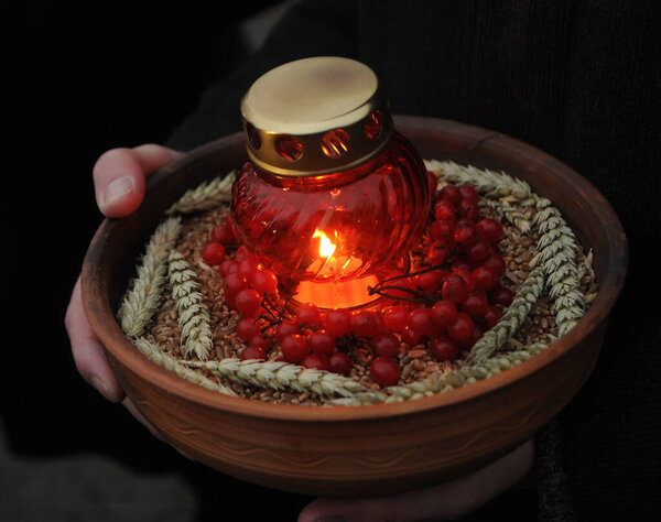 A lighted icon lamp on a clay plate near the sculpture "Bitter memory of childhood" on the Day of Remembrance of the Victims of Holodomors in Kiev, November 28, 2020