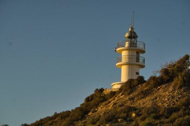 Sahilde güzel bir gün doğumu, arka planda bir deniz feneri, Alicante, İspanya 'da. Görünüm