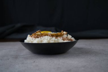 Pişmiş pirinçli siyah tabak, kızarmış yumurta ve ton balığı masada. yiyecek