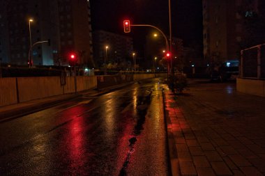 Yağmurlu bir günde kırmızı trafik ışıkları ve ıslak caddede gece yansıması. görünüm