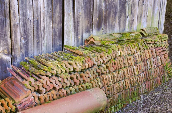 Ahşap duvarın önündeki eski çatı kiremitleri yığını
