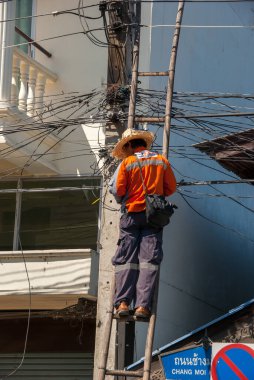 14.11.2011, Chiang Mai, Tayland. Bir kablo teknisyeni merdivende durur ve elektrik direği üzerinde çalışır..