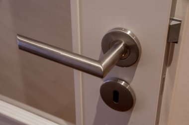 Paslanmaz çelik iticili beyaz bir kapının ayrıntılı görüntüsü.