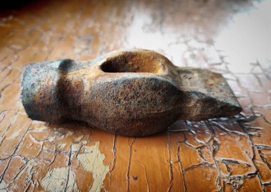 Paslı eski bir çekiç, turuncu bir yüzeyde yatıyor.