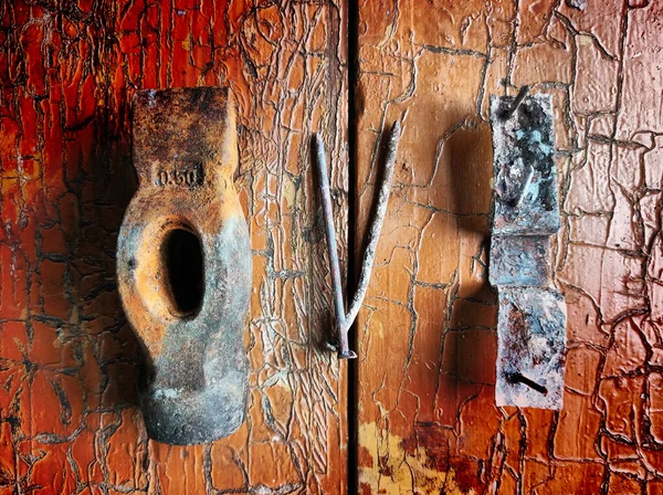 An old rusty hammer lies on a rough orange surface with cracks